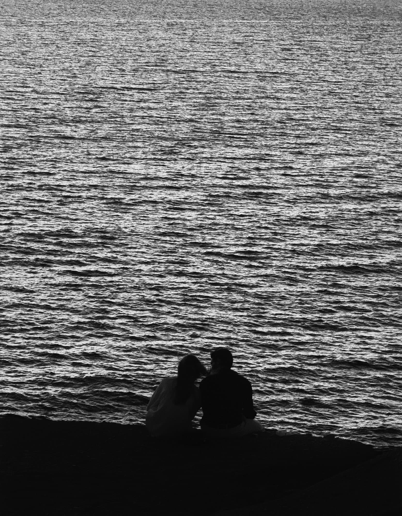 Zwart-witfoto van twee mensen die samen naar de zee kijken